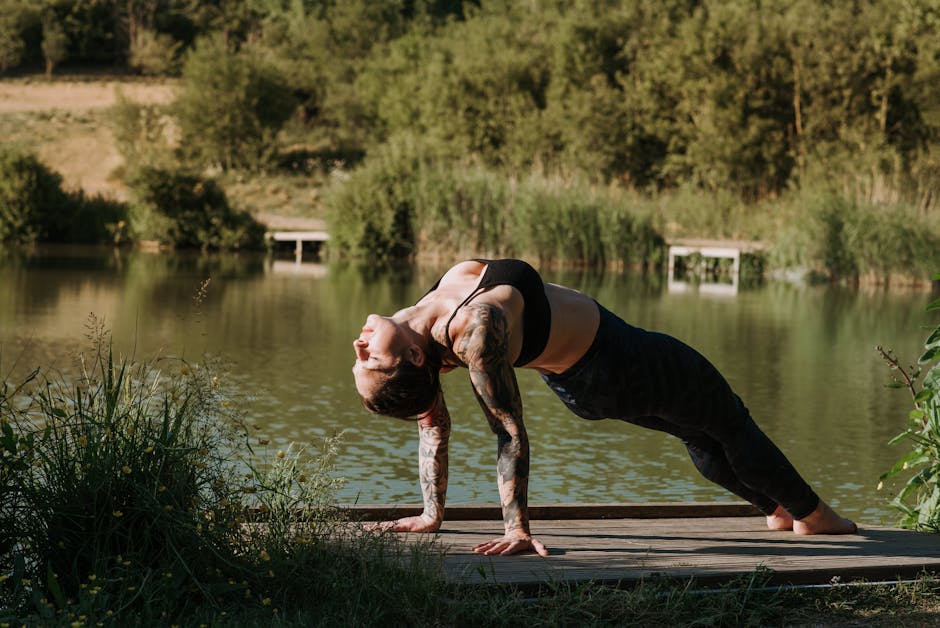 Woman practicing a peaceful yoga pose on a wooden pier next to a calm lake.